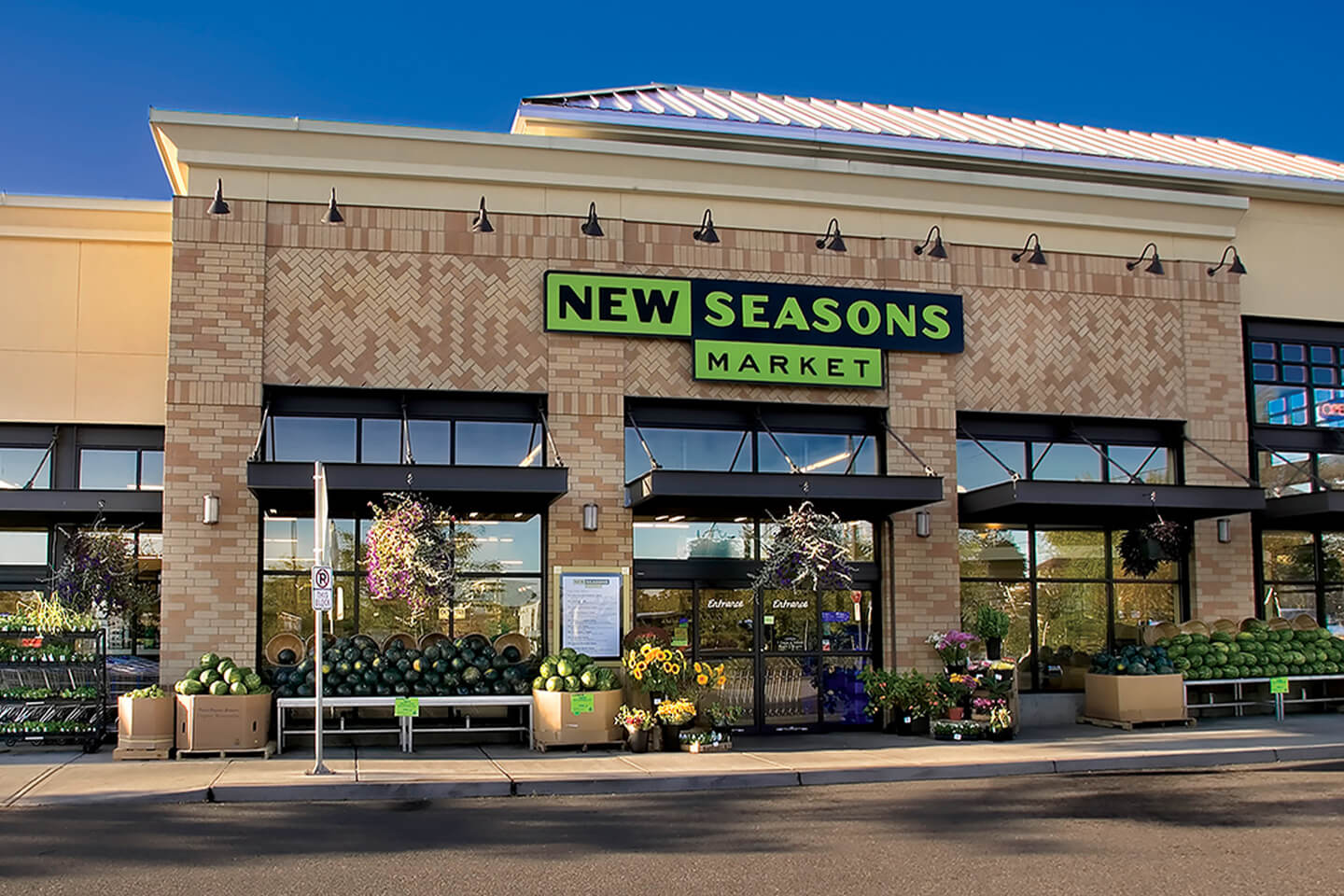 a photo of the exterior of a New Seasons Market grocery store on a sunny day.